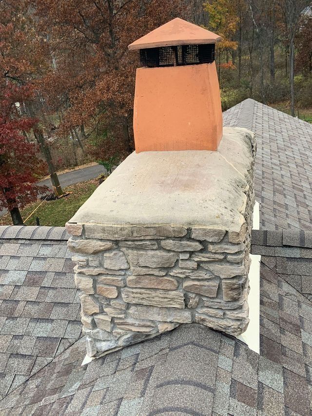 Brick chimney on a roof, with a metal cap and flashing.