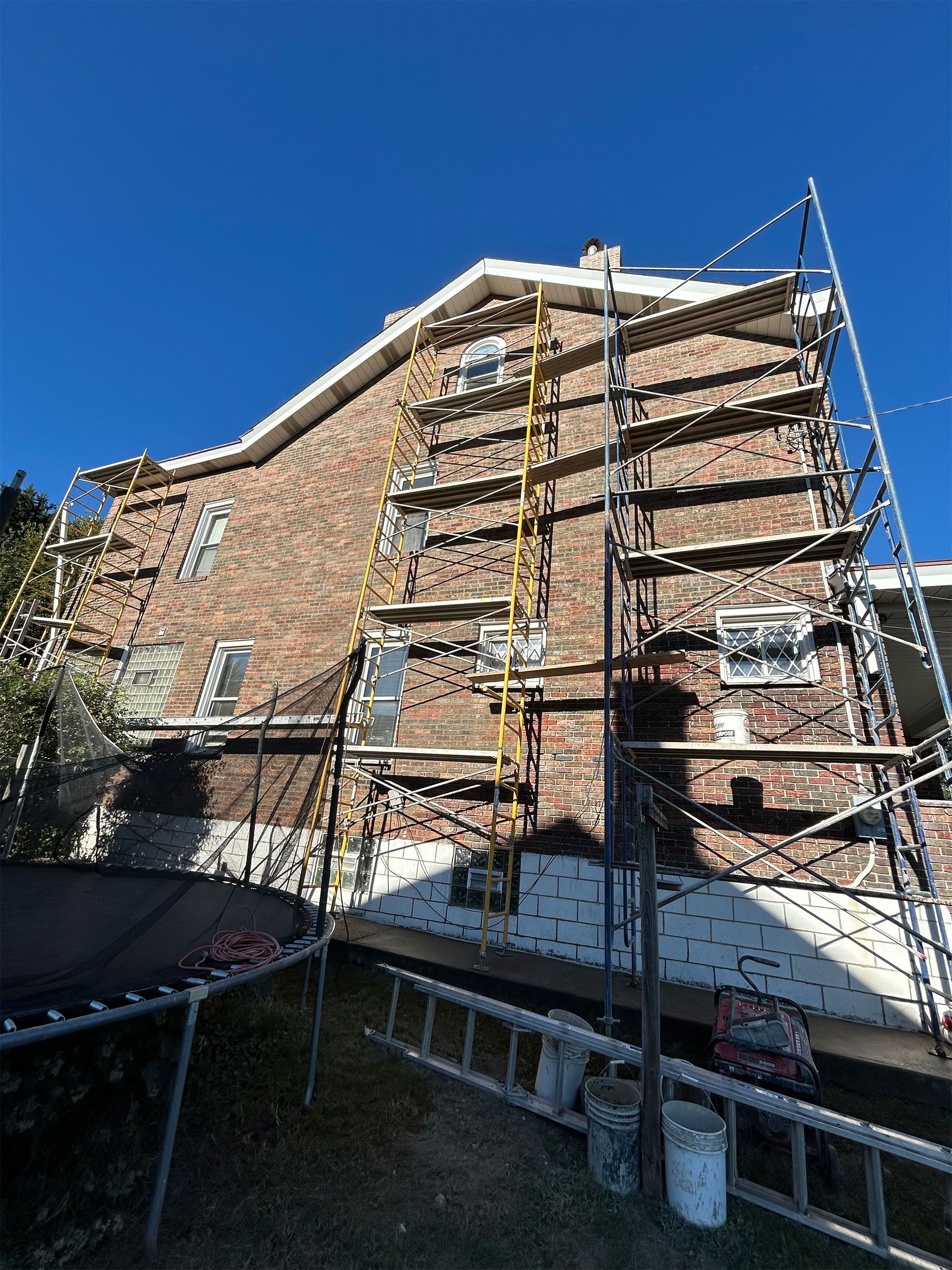 Brick building with scaffolding set up for construction against a clear blue sky.
