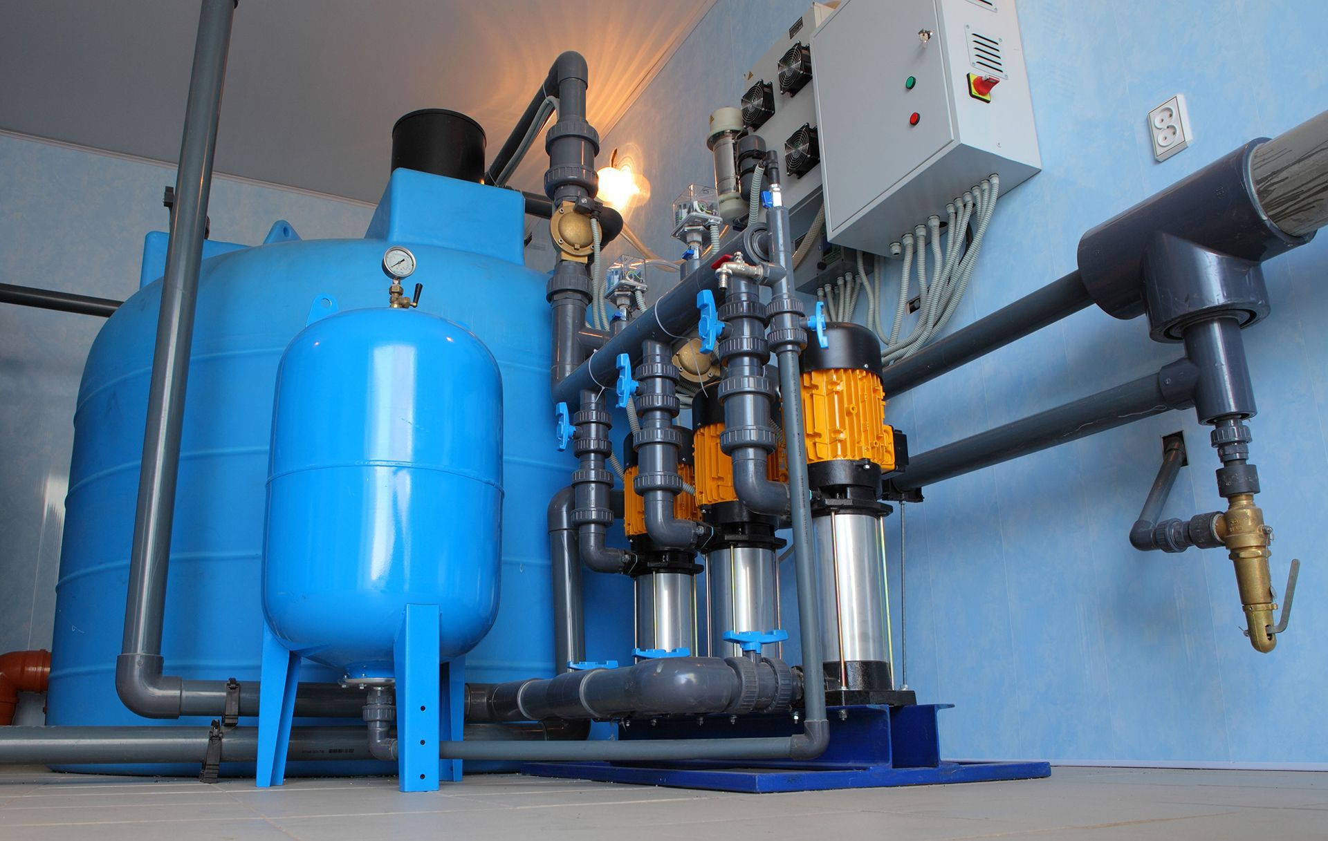 blue water treatment system with tanks, pumps, and pipes inside a room