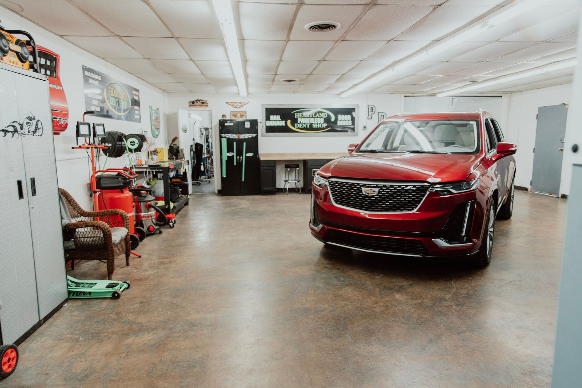 Red SUV in a well-lit garage with tools and storage cabinets.