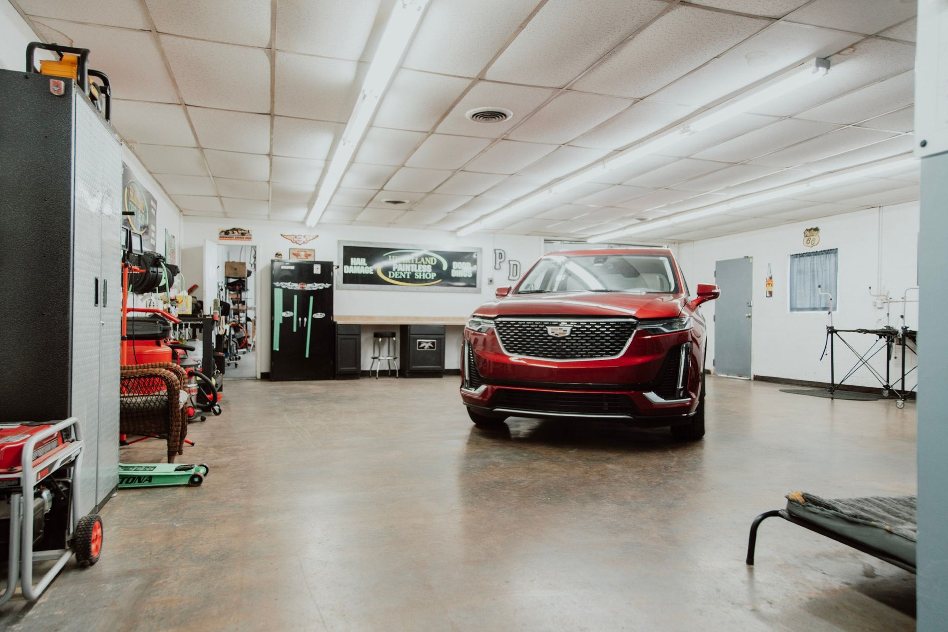 Red SUV parked in a well-lit garage, surrounded by tools and equipment.