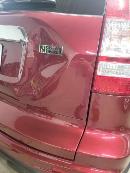 Red car rear with dent above bumper and 