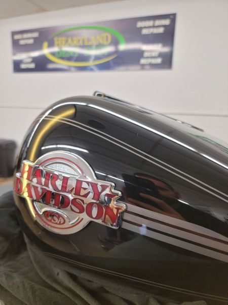 Black Harley Davidson motorcycle gas tank with logo and silver stripes.