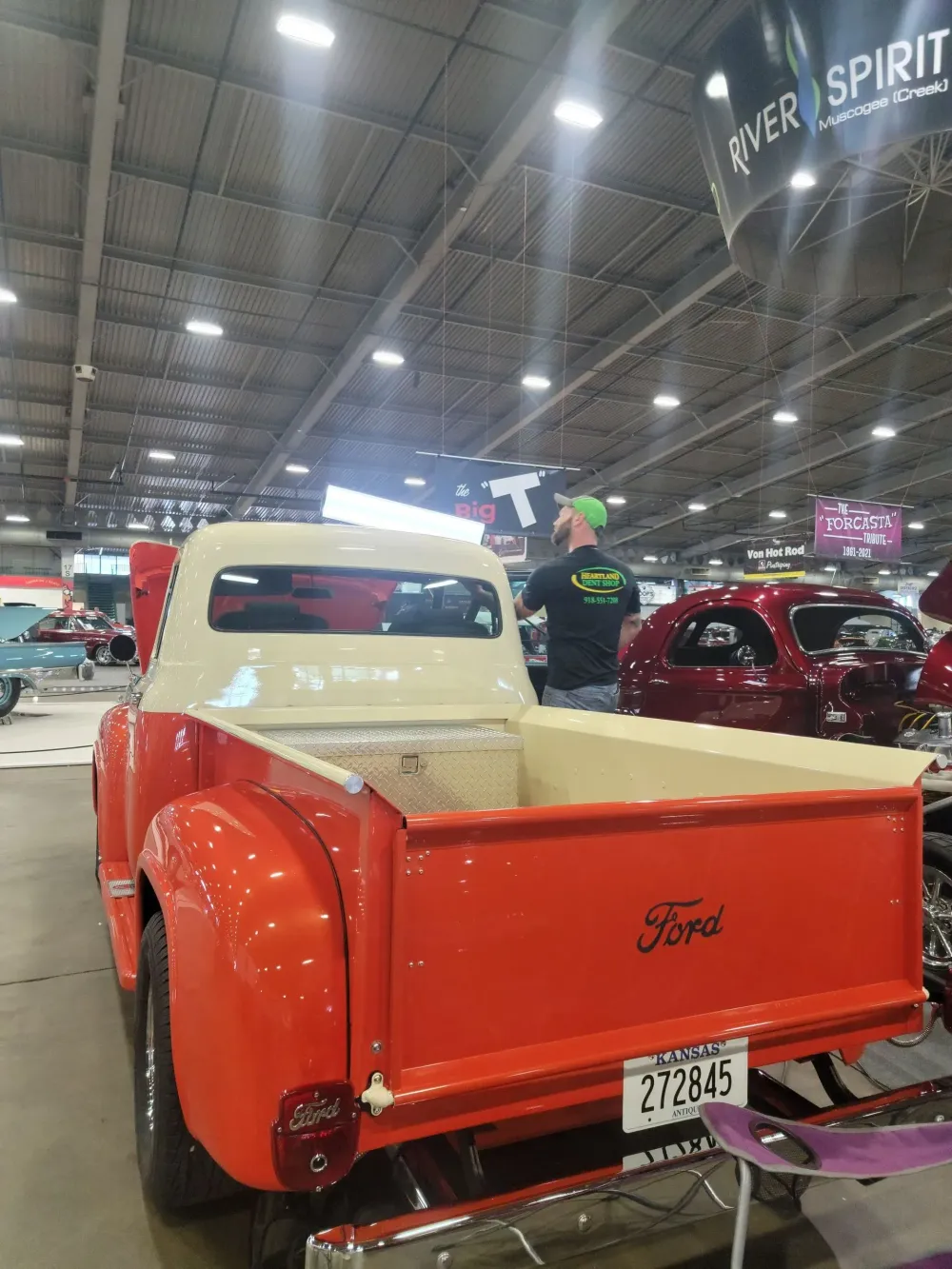 Red and white vintage Ford pickup truck on display at an indoor car show.