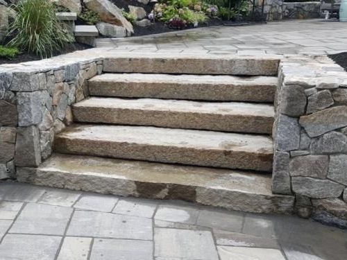 A set of stone stairs leading up to a stone wall.