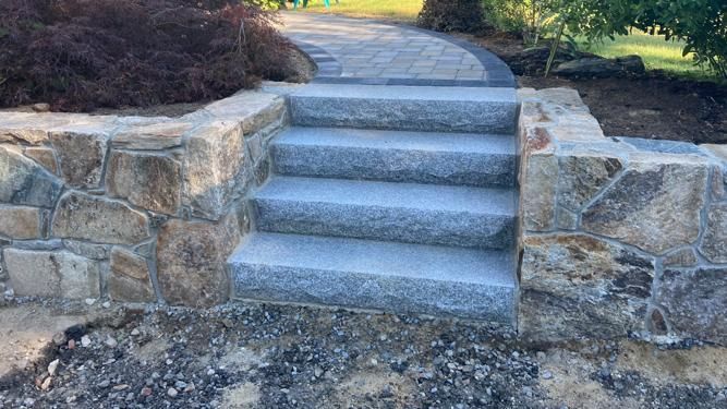 a stone walkway with stairs leading up to a stone wall.