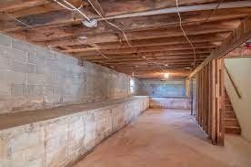 Basement interior with cinder block walls, exposed wooden beams, and unfinished framing.