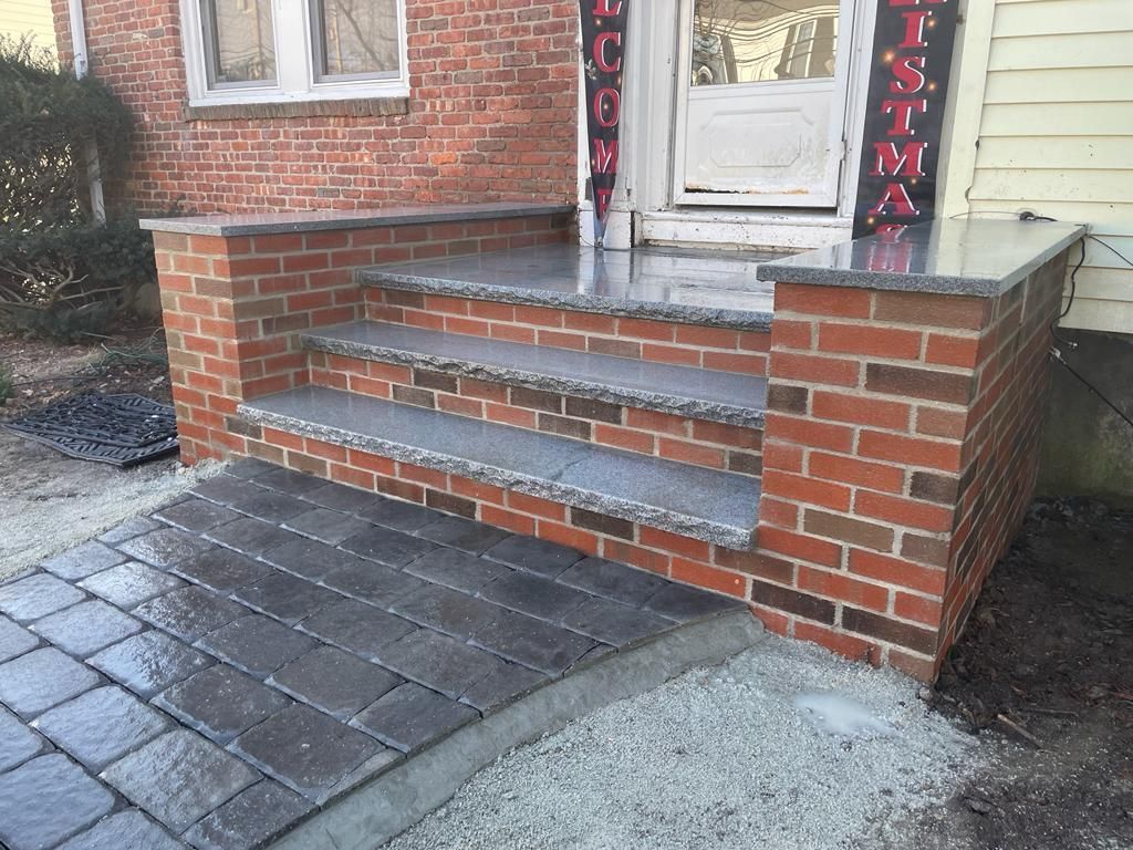 a brick porch with stairs leading up to the front door of a house.