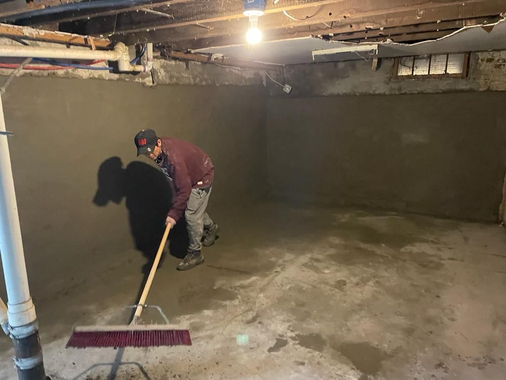a man is cleaning a basement floor with a broom.