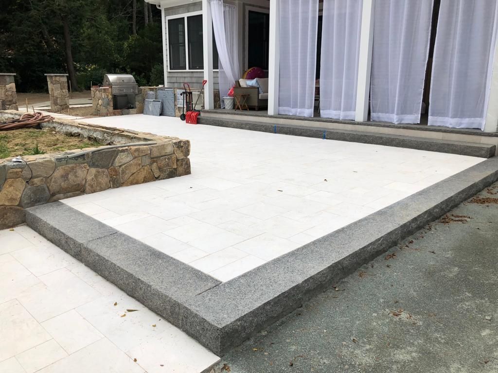 a white patio with a black border is being built in front of a house.