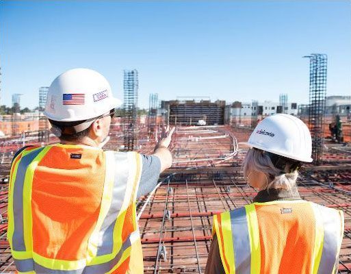 The two professional workers are looking at a construction site.