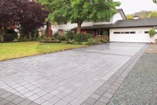 A driveway leading to a house with a tree in the background.
