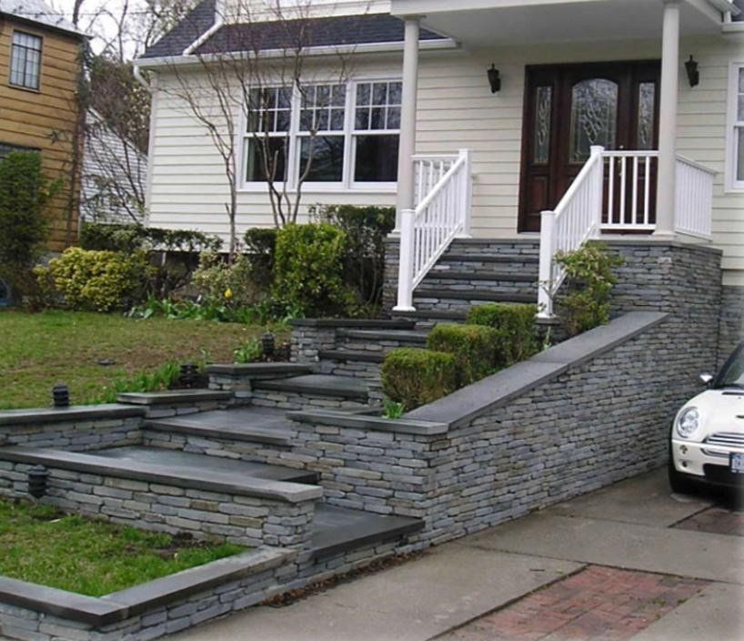 Stone steps leading up to a house with white trim and a brown door, a car parked nearby.