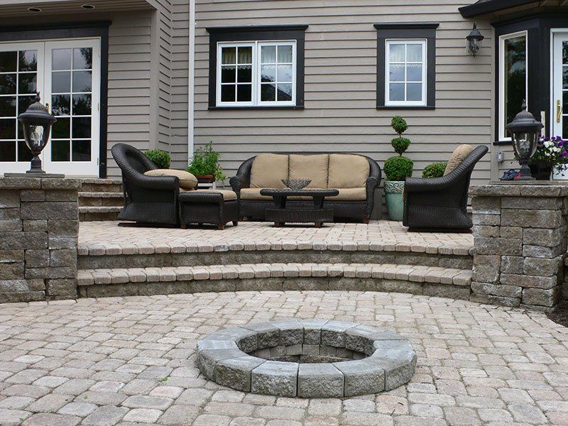 A patio with outdoor furniture, a fire pit, and a house in the background.