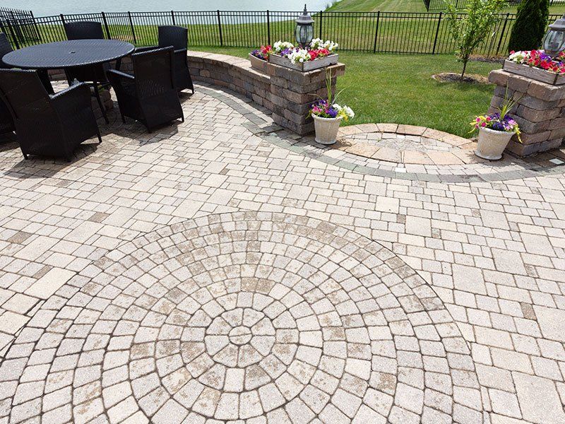 Brick patio with circular design, seating area, and flower boxes.