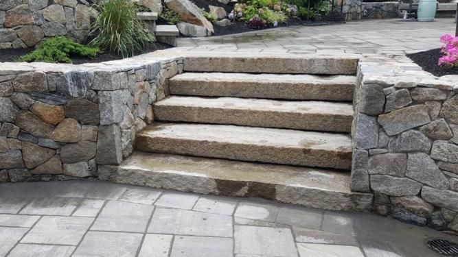 Stone steps between stone walls on a patio.