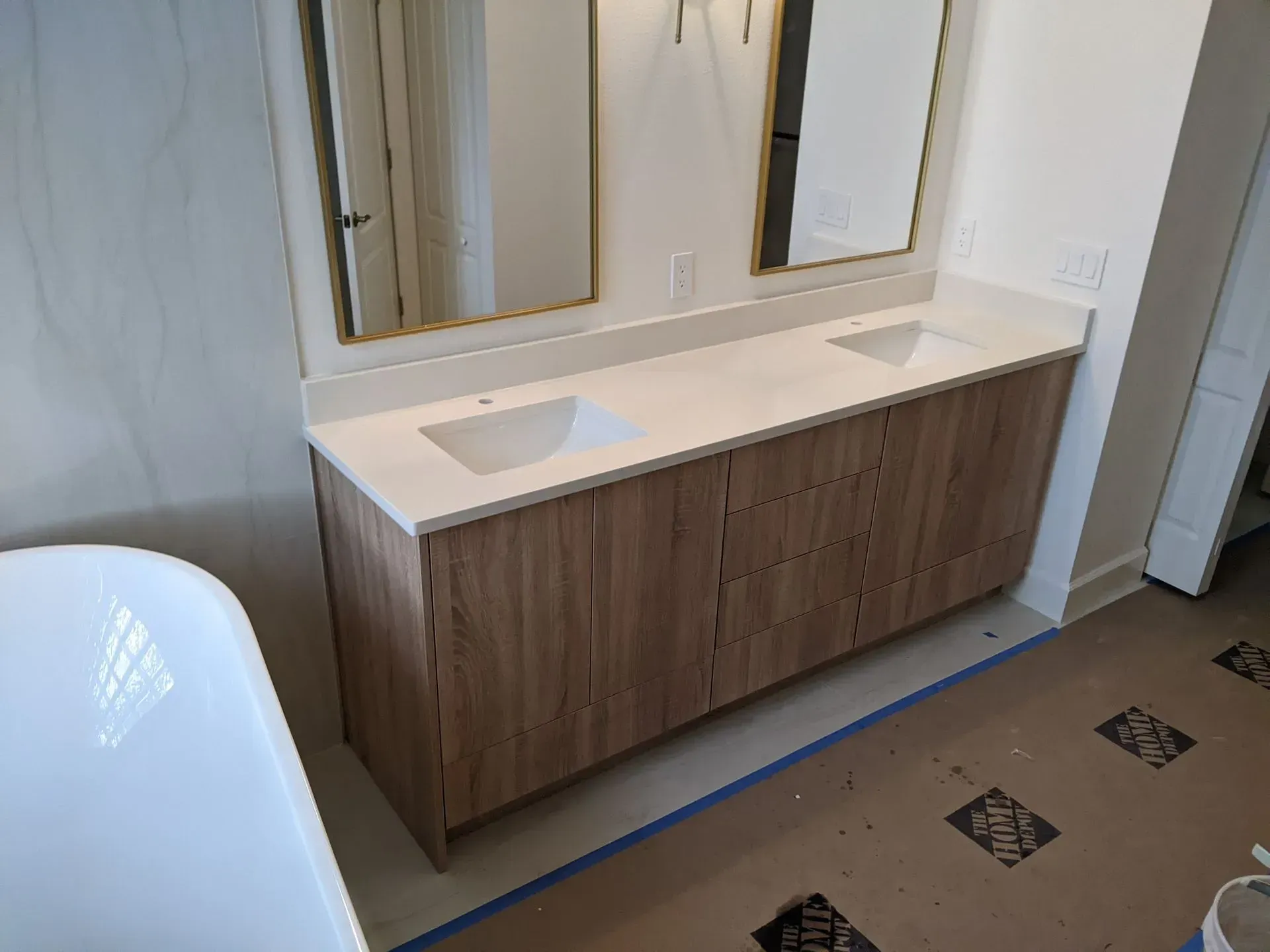 Bathroom vanity with double sinks, wood cabinet, and mirrors above a tiled floor.