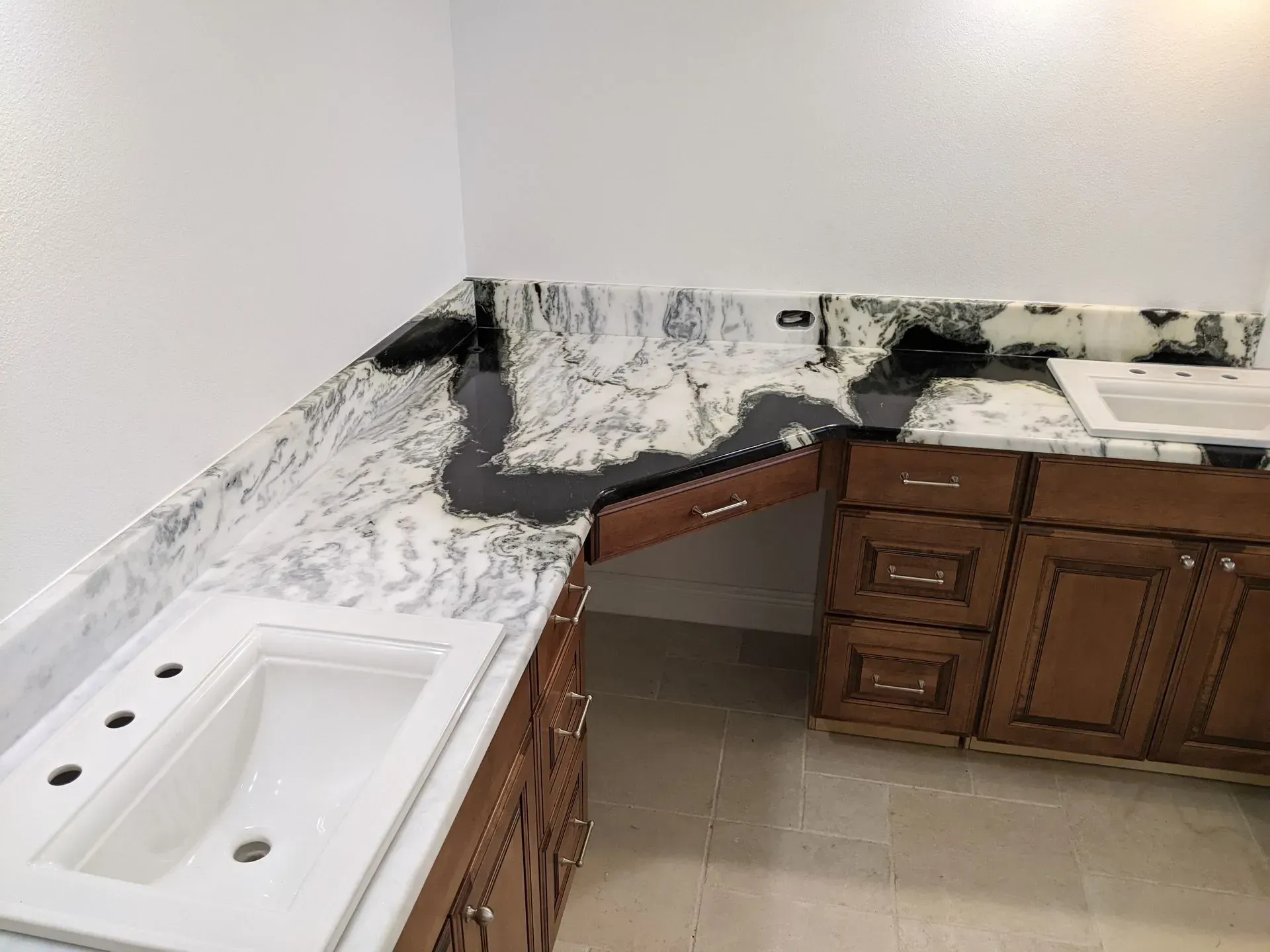 Damaged kitchen countertop with white and black marble pattern, cabinets, and sink in a corner room