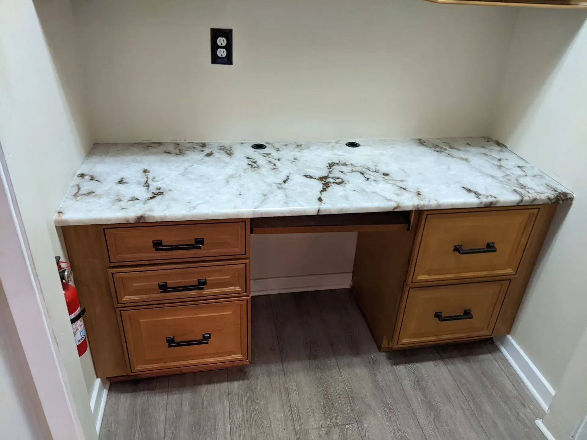 Empty wood desk with white marble top in a small room, featuring drawers on both sides.