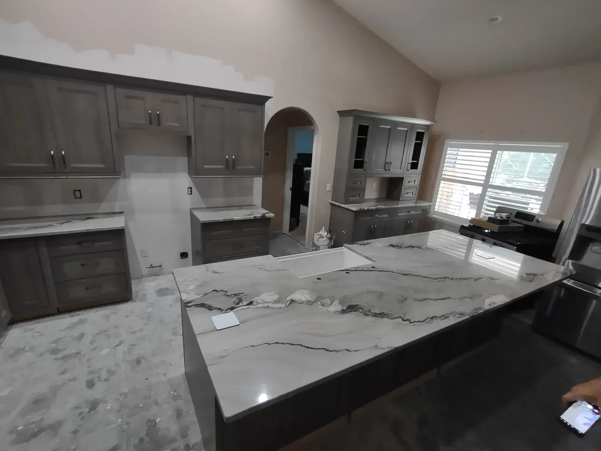 Modern kitchen with dark wood cabinets, white marble island, and large window over sink