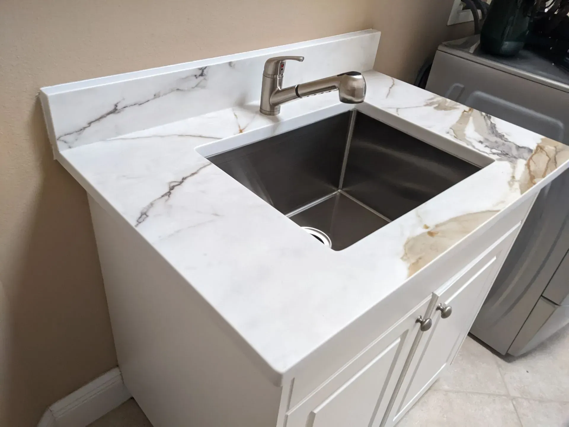 White bathroom vanity with marble countertop and stainless-steel sink and faucet