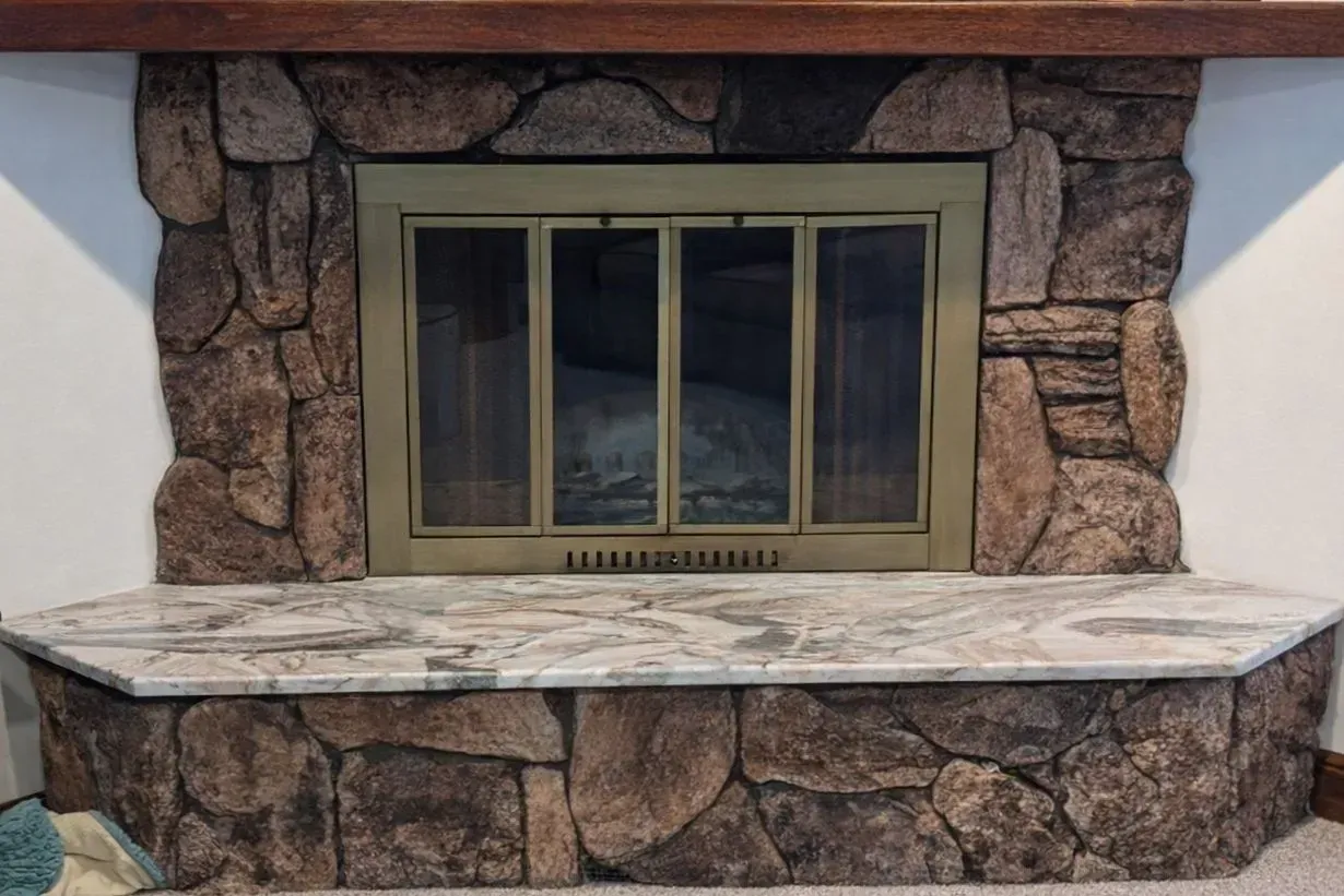 Stone fireplace with a central window and wide stone ledge beneath a wooden mantel