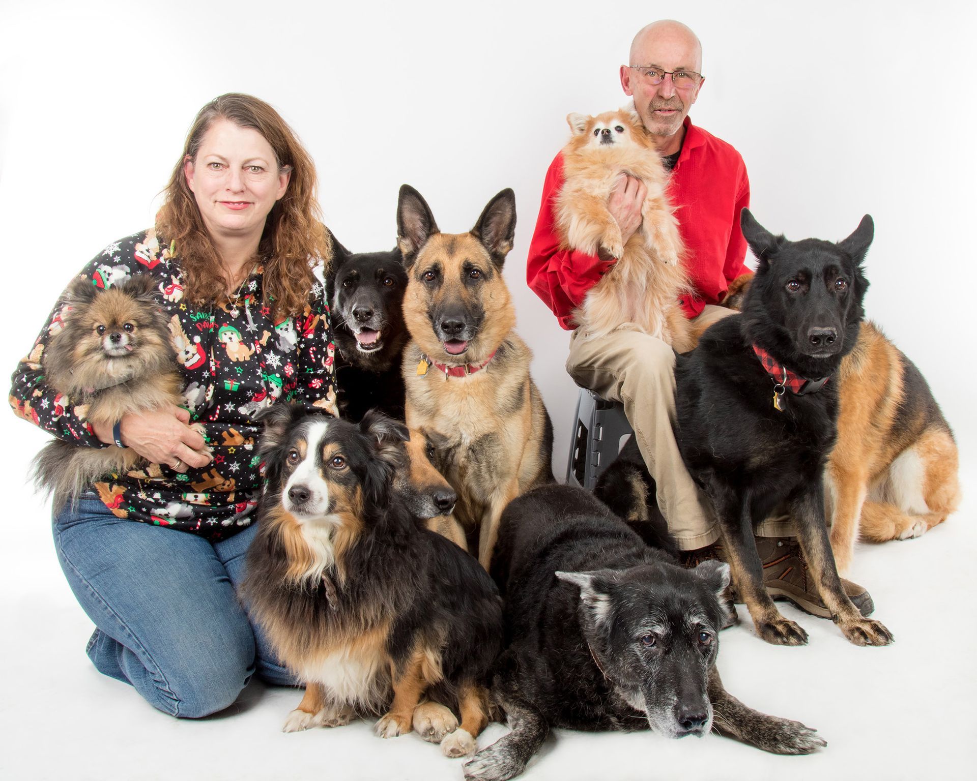 A man and a woman are posing for a picture with their dogs