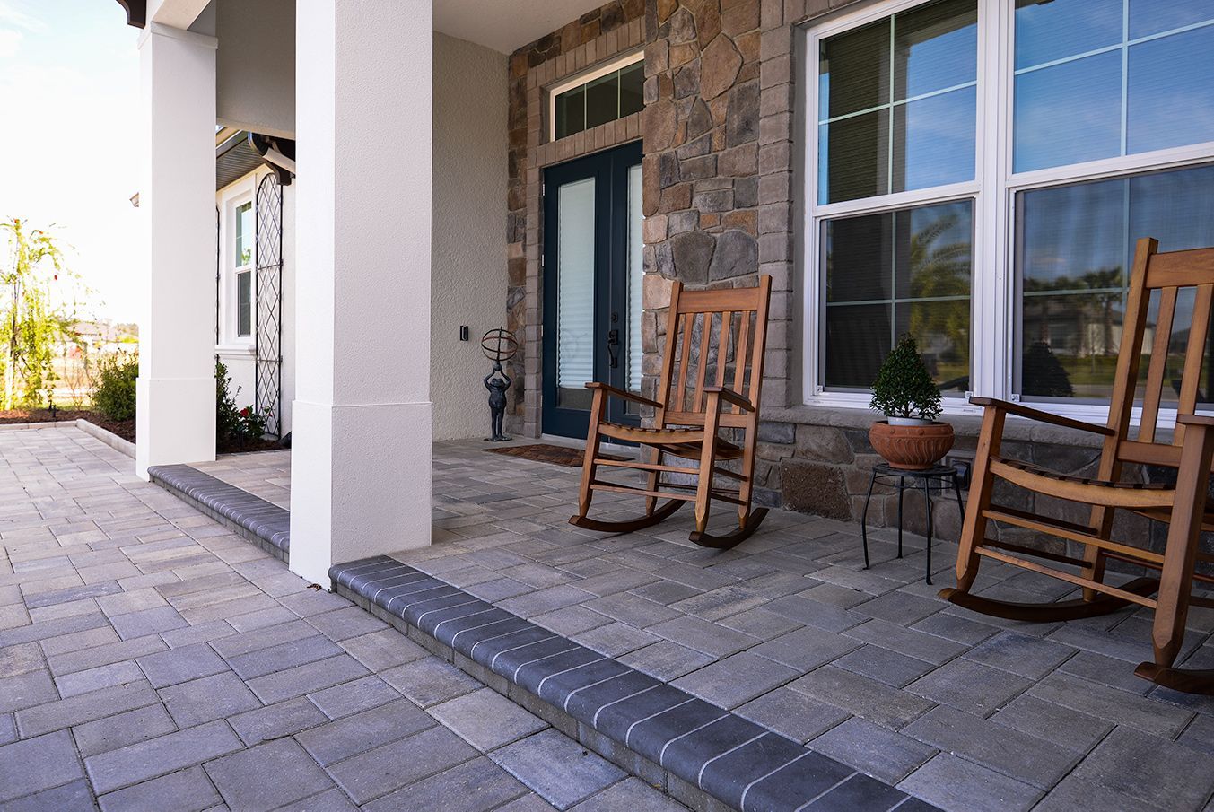 There are two rocking chairs on the porch of a house.