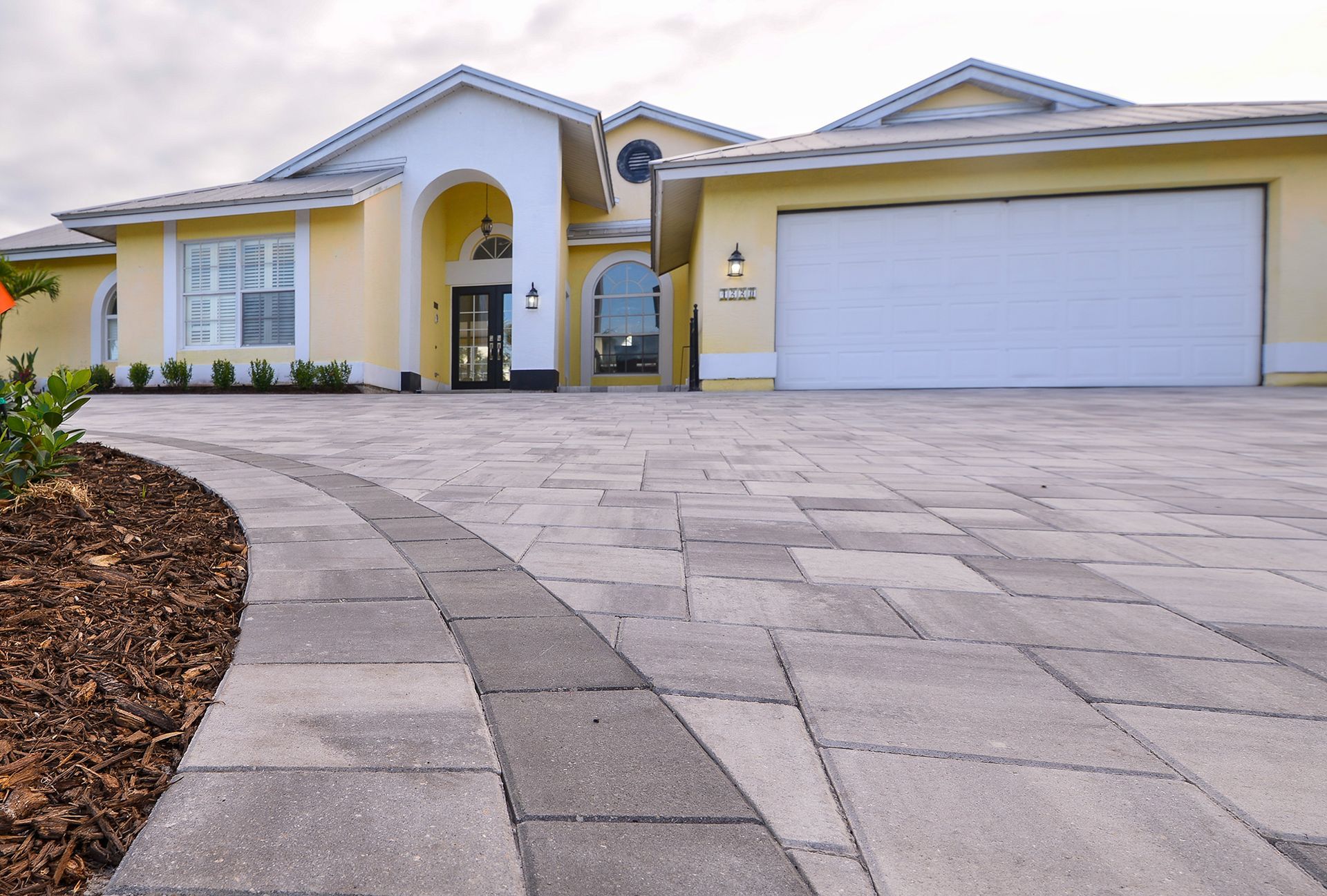A large yellow house with a white garage door.