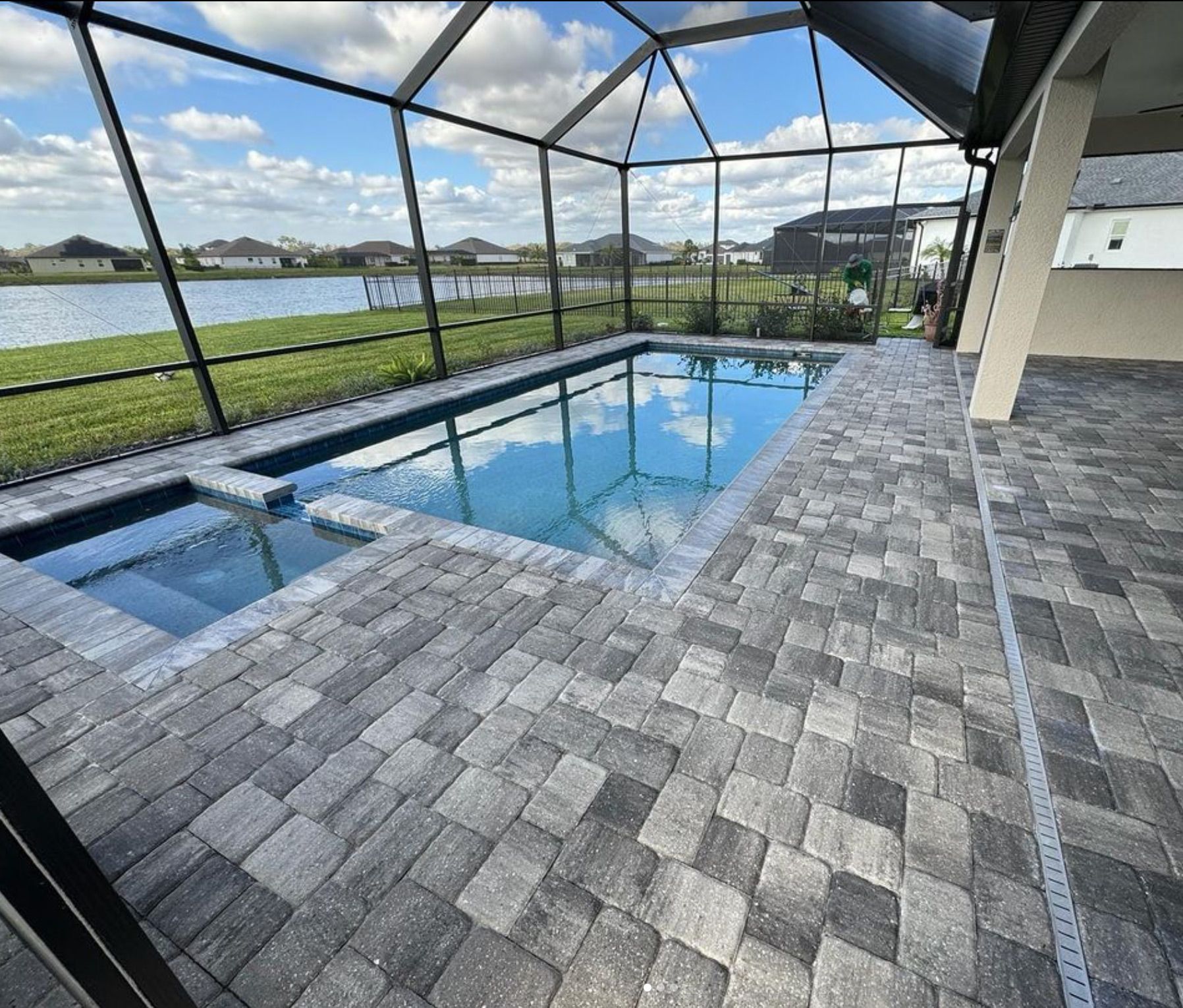 A large swimming pool is surrounded by a screened in area.