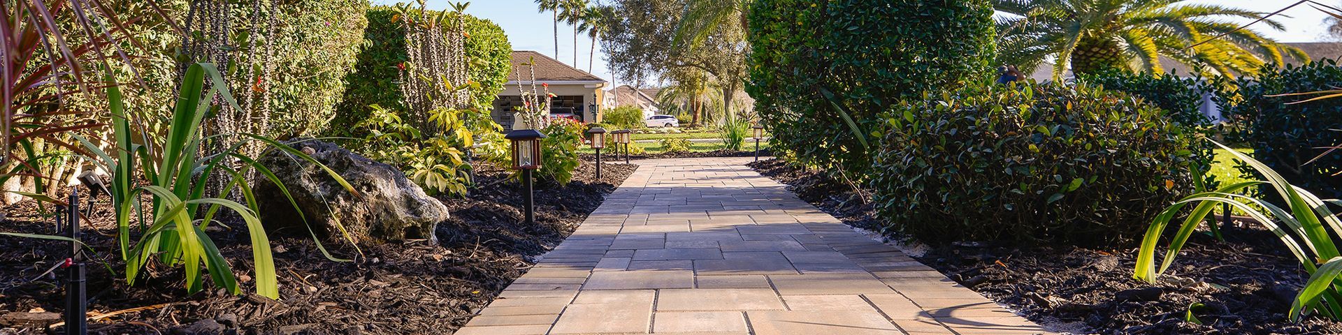 A stone walkway surrounded by trees and bushes in a park.