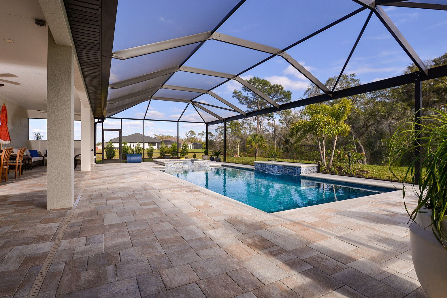 A large swimming pool is surrounded by a screened in area.