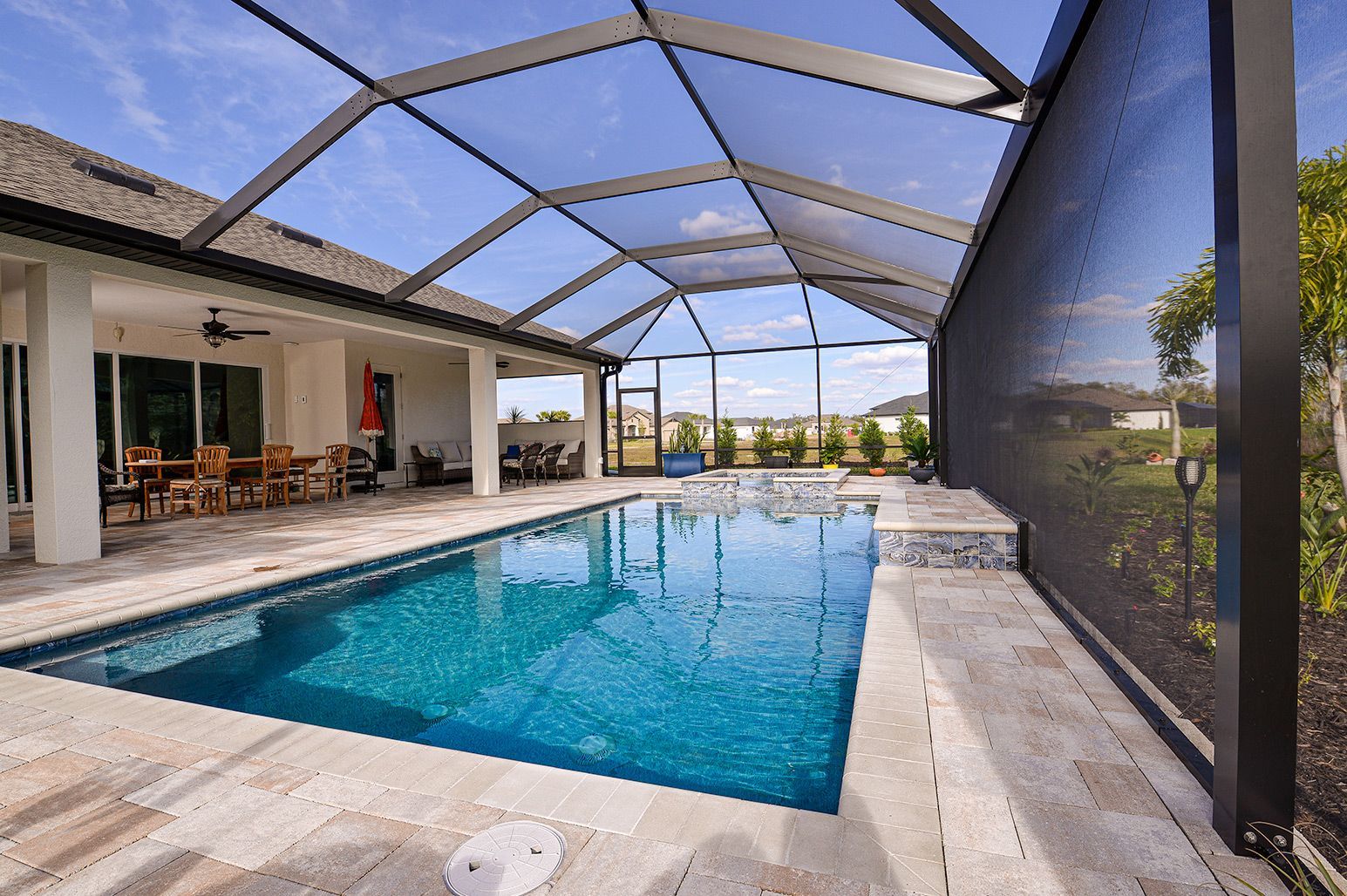 A large swimming pool is surrounded by a screened in area.