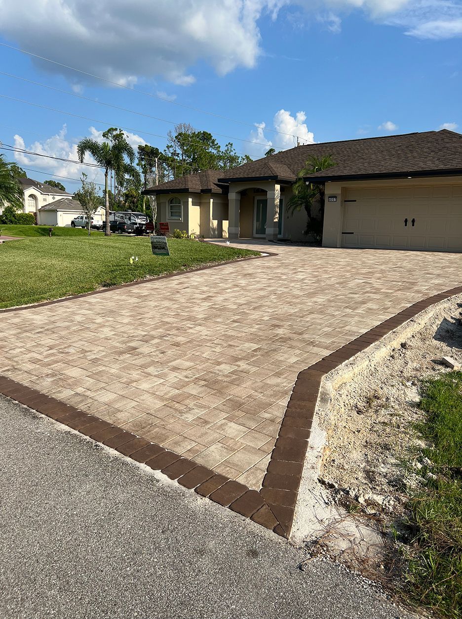 A brick driveway leading to a house with a garage.