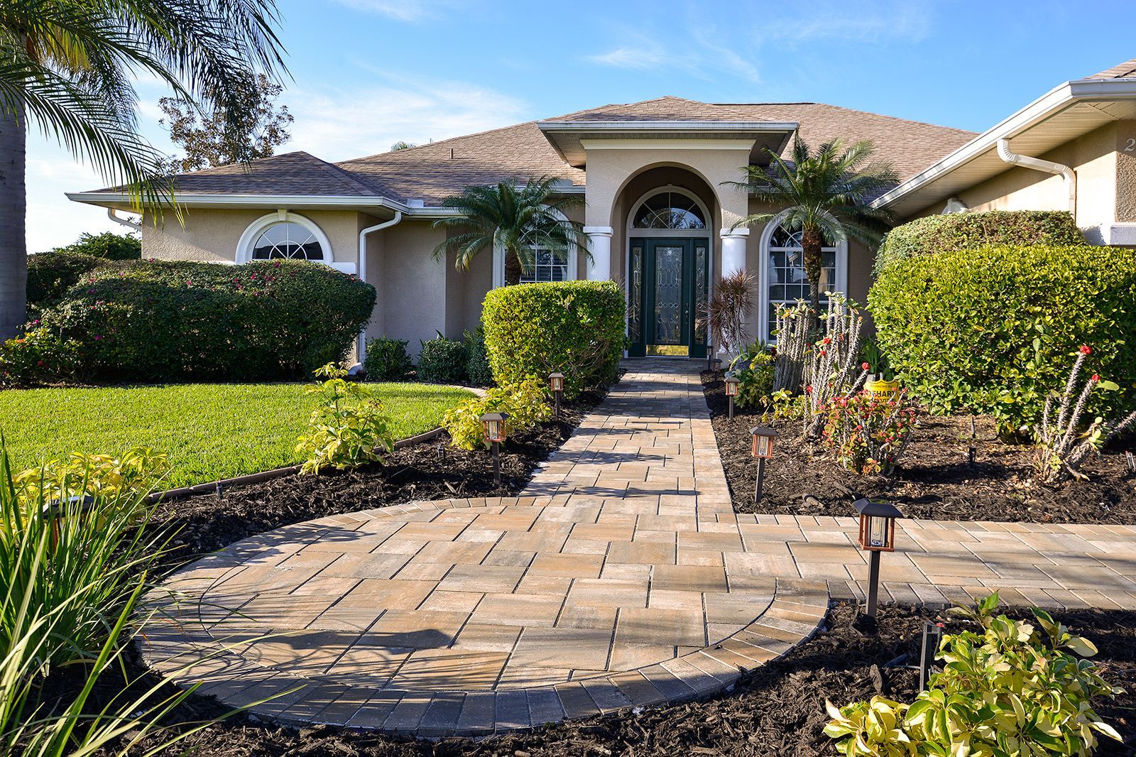 A large house with a brick walkway leading to the front door.