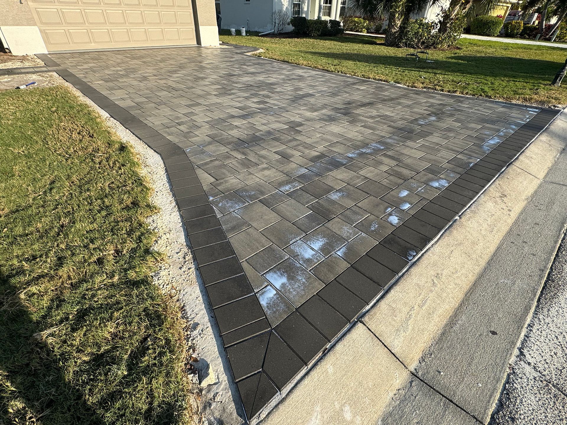 A brick driveway is being built in front of a house.