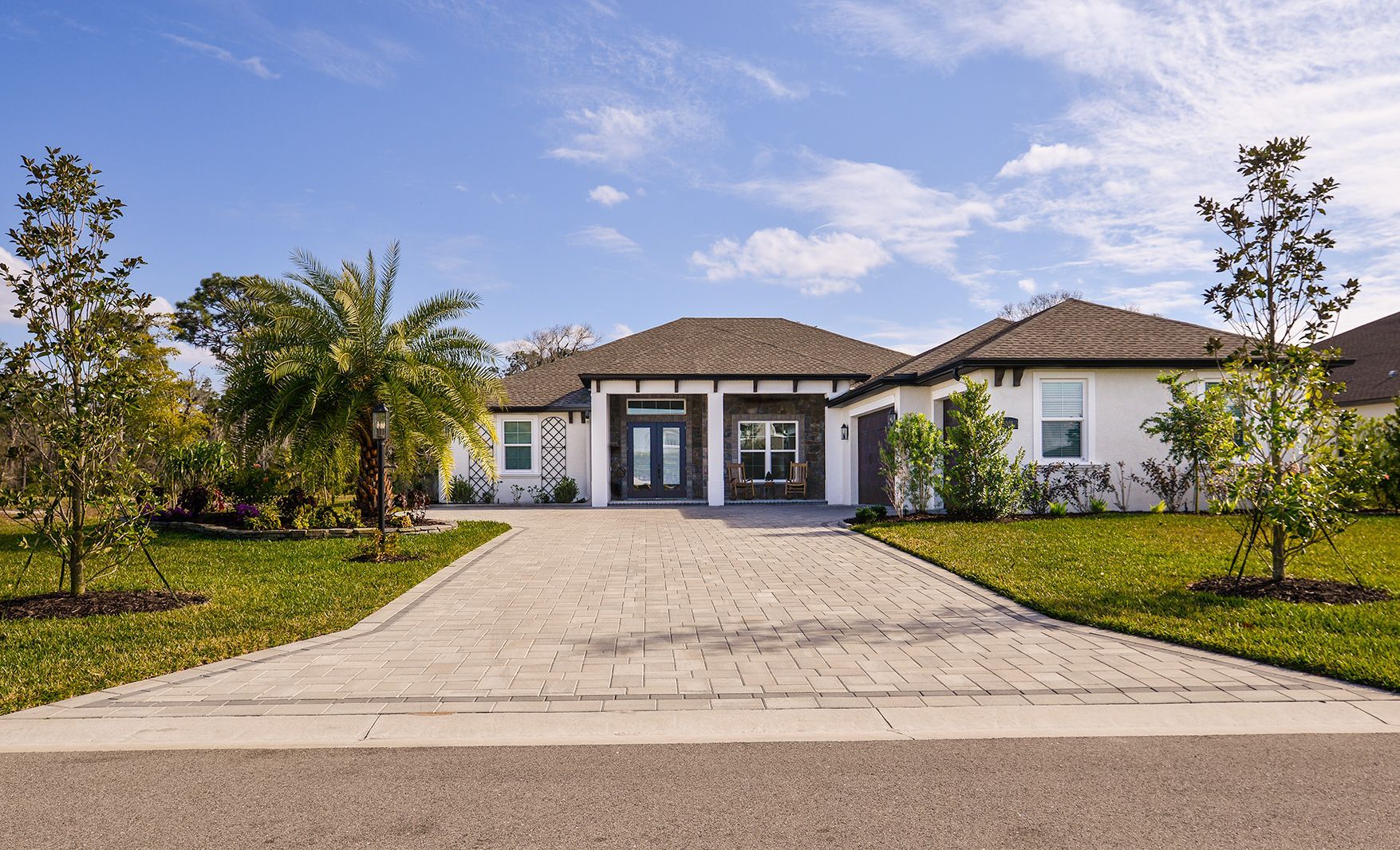 A large white house with a driveway and trees in front of it.