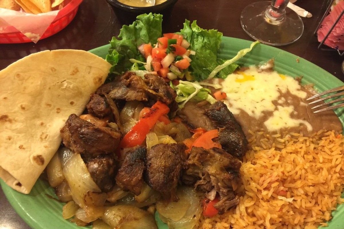 A green plate topped with meat rice and a tortilla