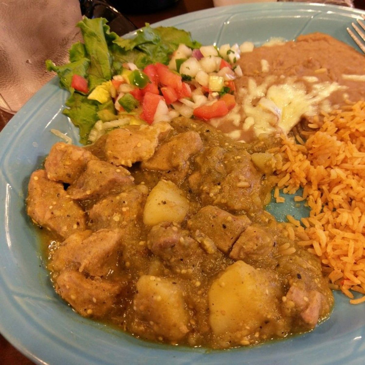 A plate of food with meat rice and vegetables on a table