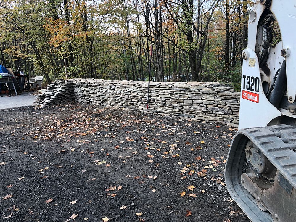 A bulldozer is parked in front of a stone wall.