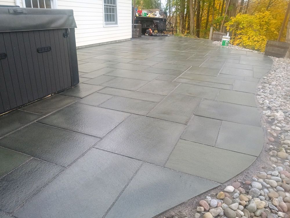 A patio with a hot tub in the background and a house in the background.