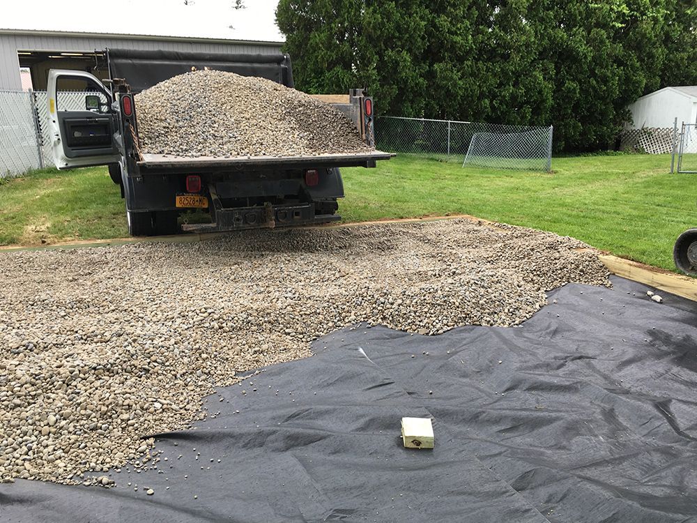 A dump truck is loaded with gravel in a driveway.