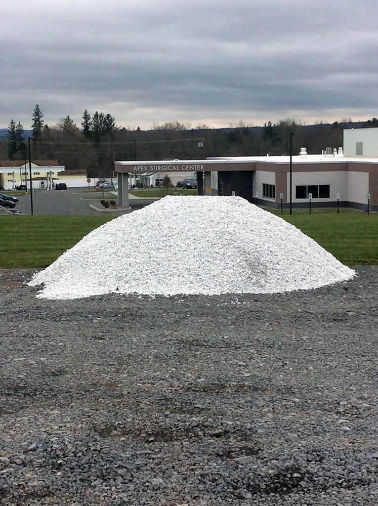 A pile of gravel is sitting on top of a gravel road in front of a building.