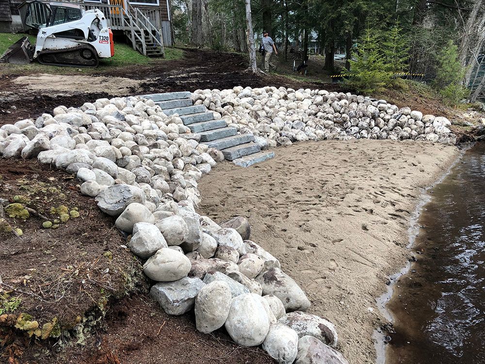 A large pile of rocks is sitting next to a body of water.