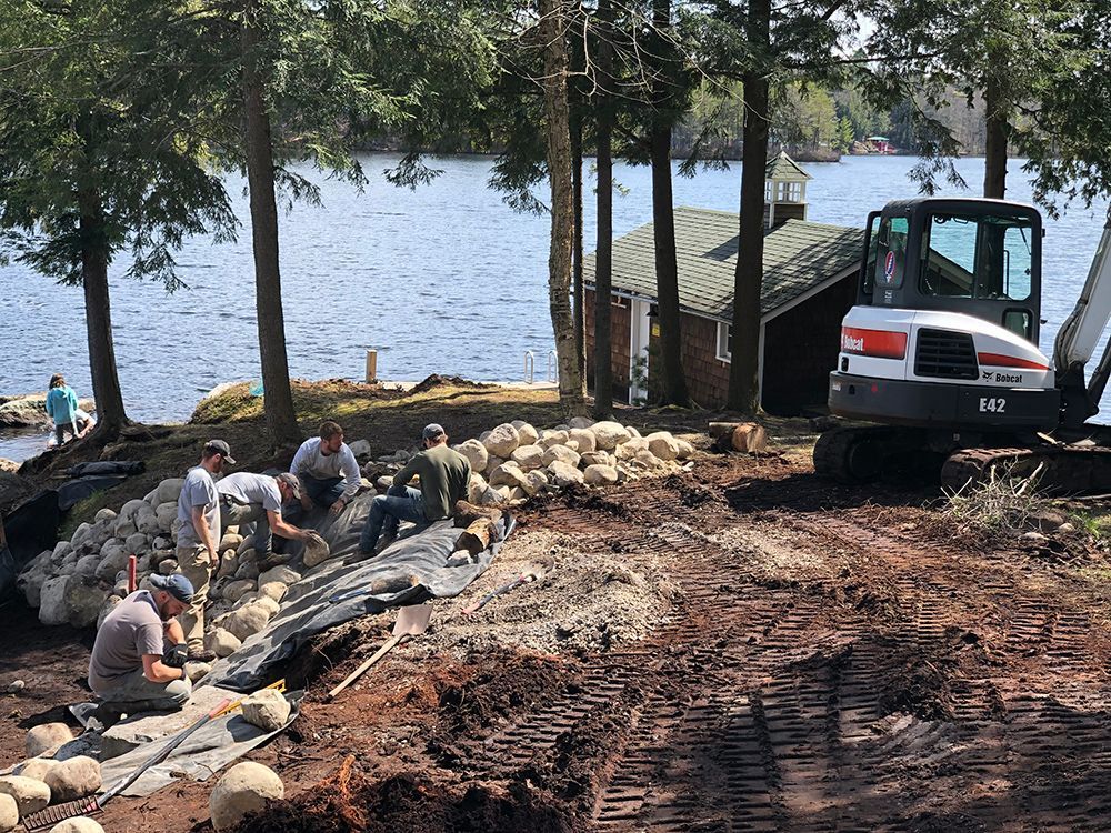 A group of people are working on a construction site next to a body of water.