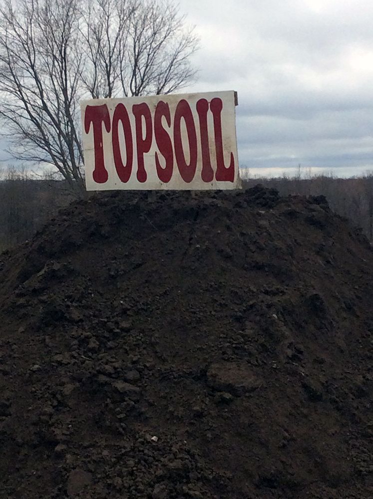 A pile of dirt with a sign that says topsoil