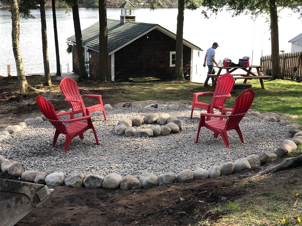 A group of red chairs are sitting around a fire pit.