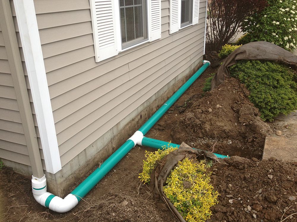 A green pipe is being installed on the side of a house.