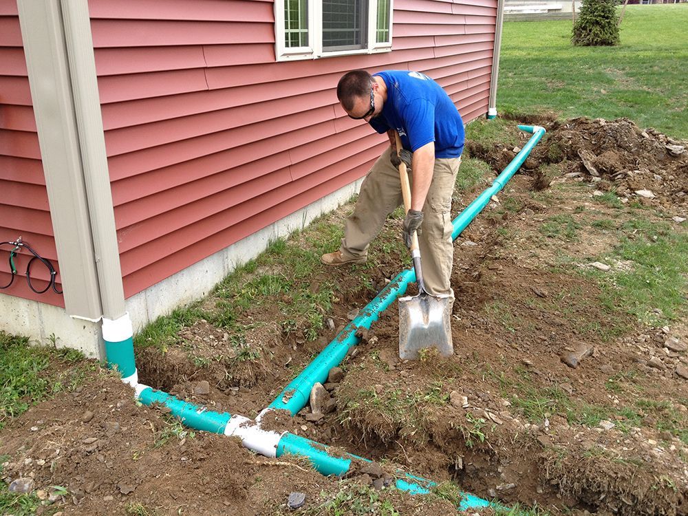A man is digging a hole with a shovel in front of a house
