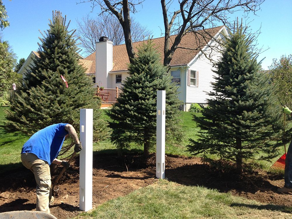 A man is digging in the dirt in front of a house